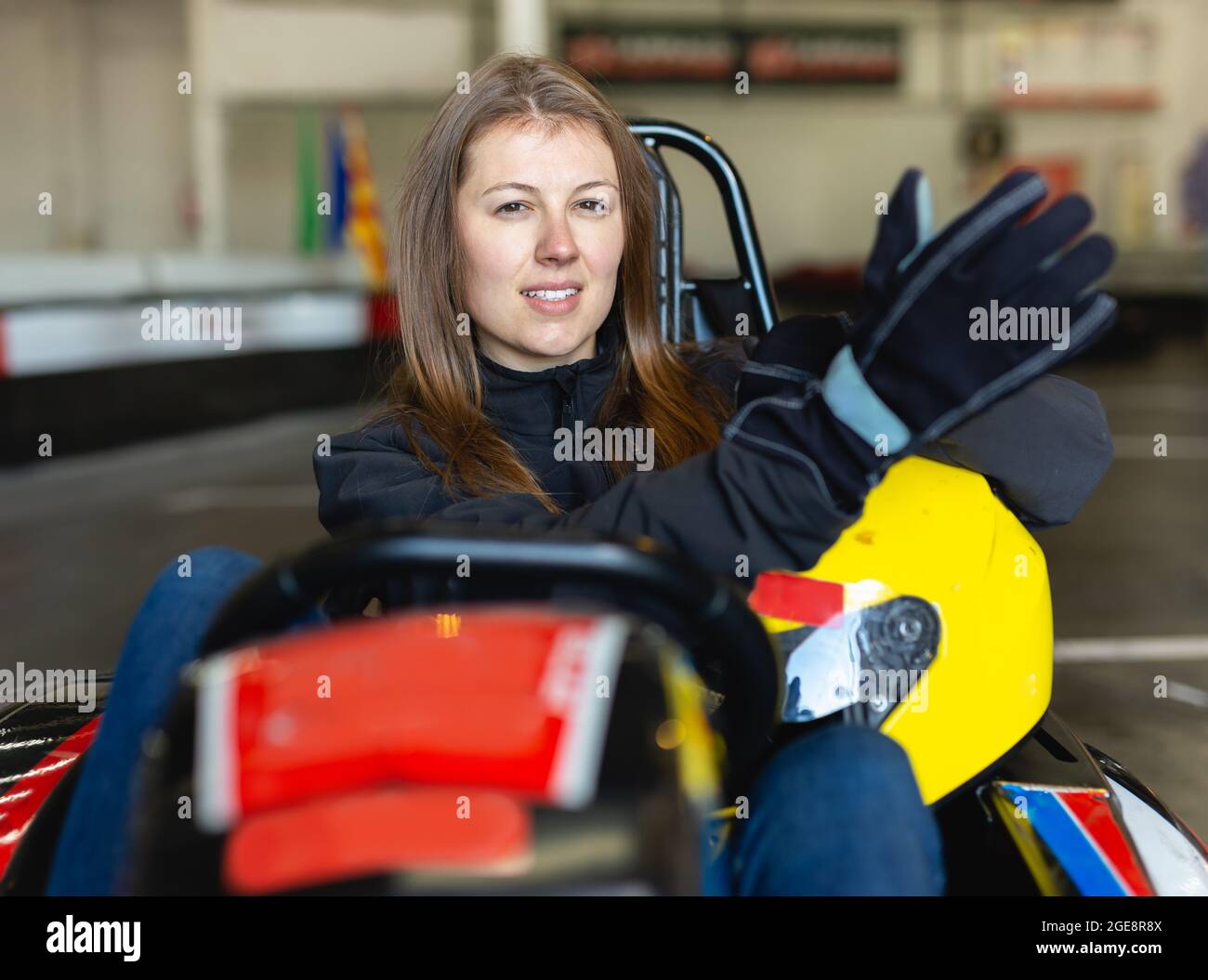 Weibliche Racerin mit Helm auf Kart-Strecke Stockfoto