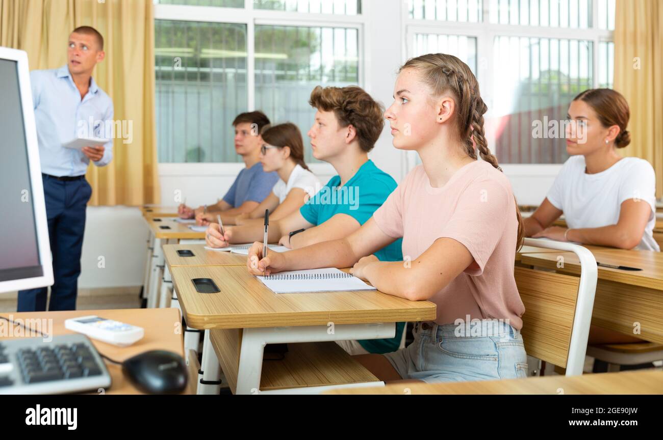 Jugendliche hören dem Dozenten zu und schreiben in Notizbüchern Stockfoto