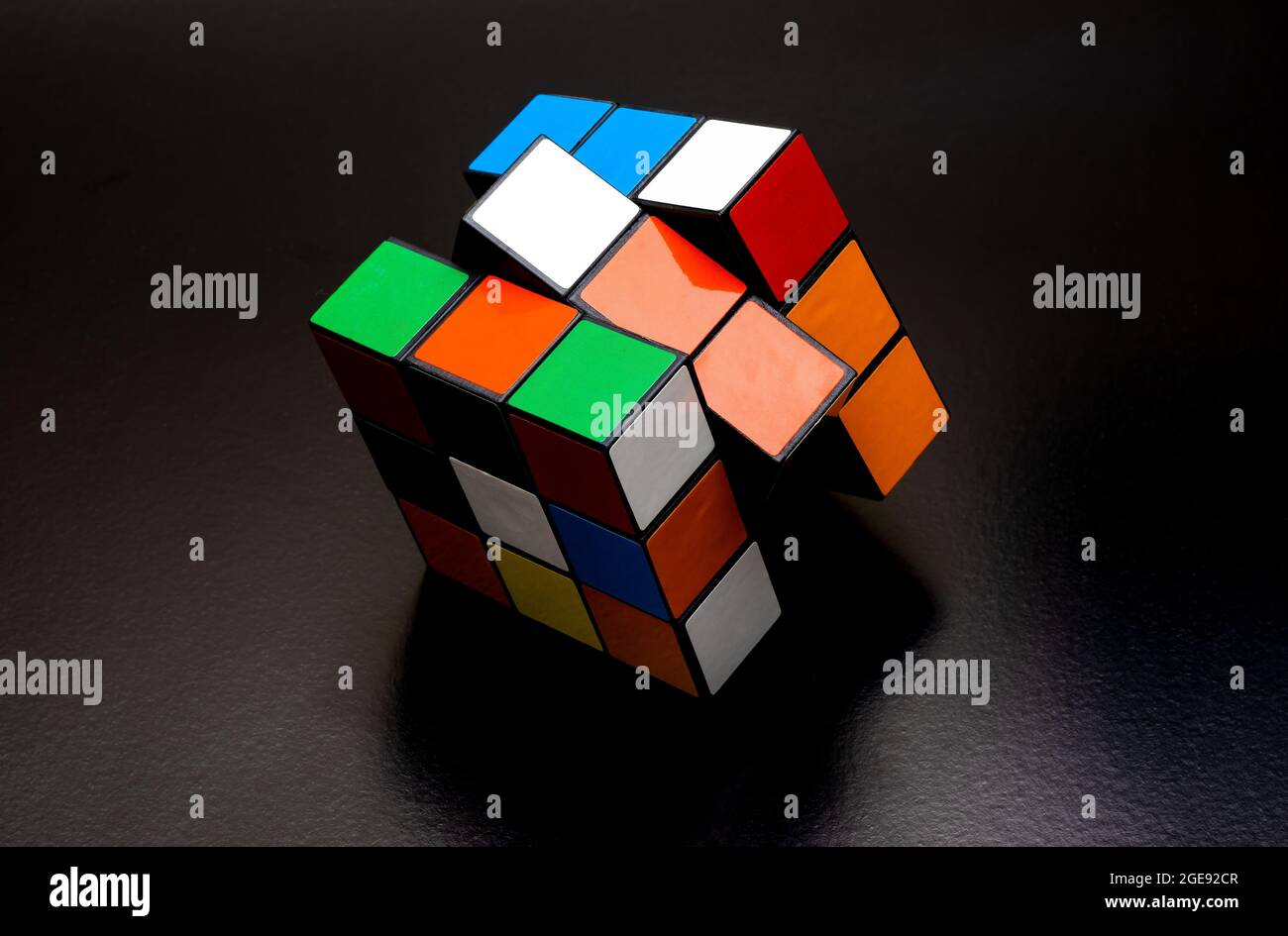 Farbenfroher rubik-Würfel mit langem Schatten auf rauem dunklen Hintergrund Stockfoto