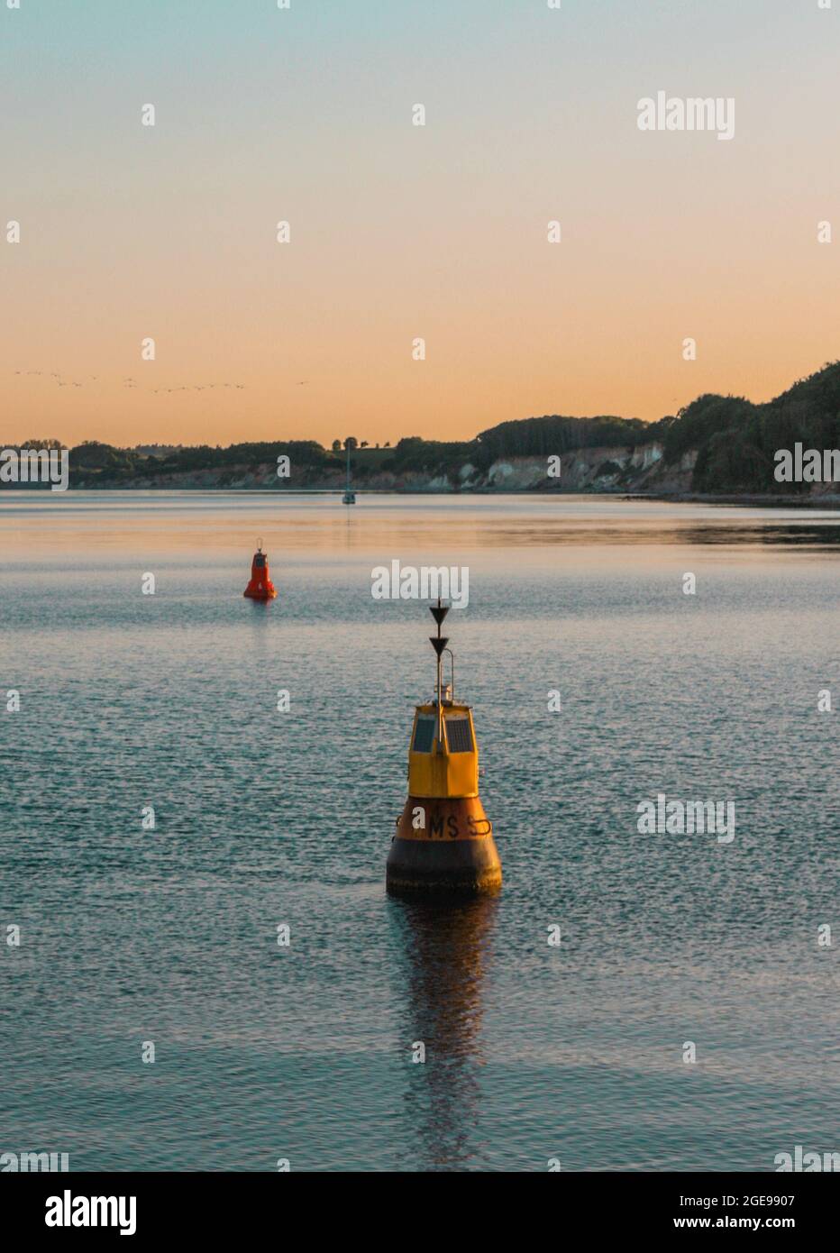 Vertikale Aufnahme von schwimmenden Bojen im Meer vor Sonnenuntergang Stockfoto