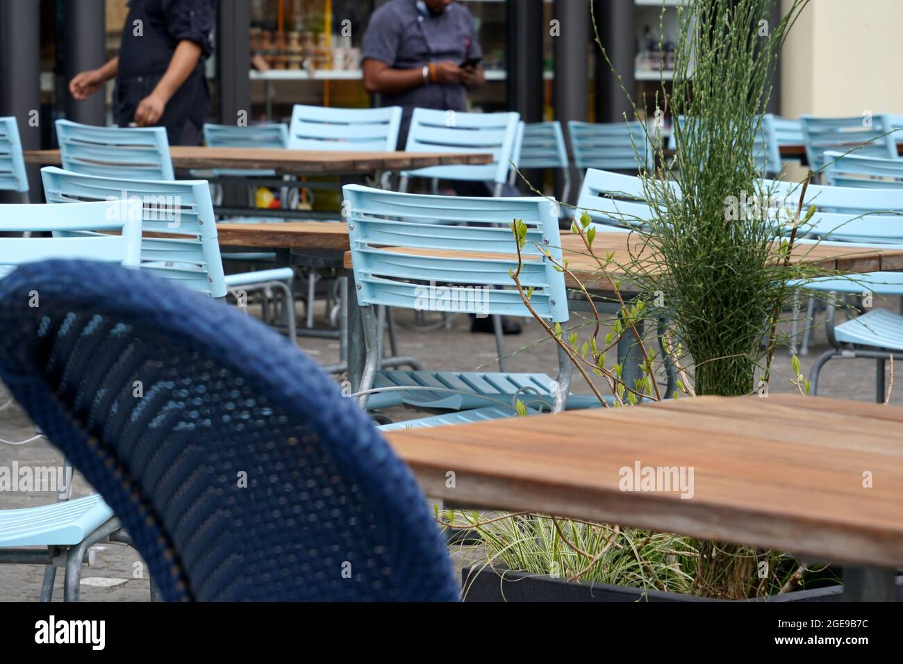 Restaurant im Freien mit leeren Tischen und Stühlen. Im Hintergrund warten Kellner auf Gäste. Stadtszene aus der Altstadt von Luzern, Schweiz. Stockfoto