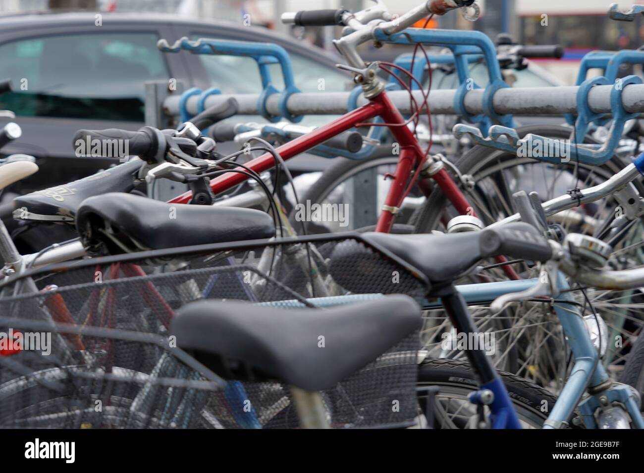 Fahrräder, die auf einer belebten Straße mit Autos geparkt wurden. Hintergrundbild zu Mobilität oder alternativem Verkehr in Städten. Stockfoto