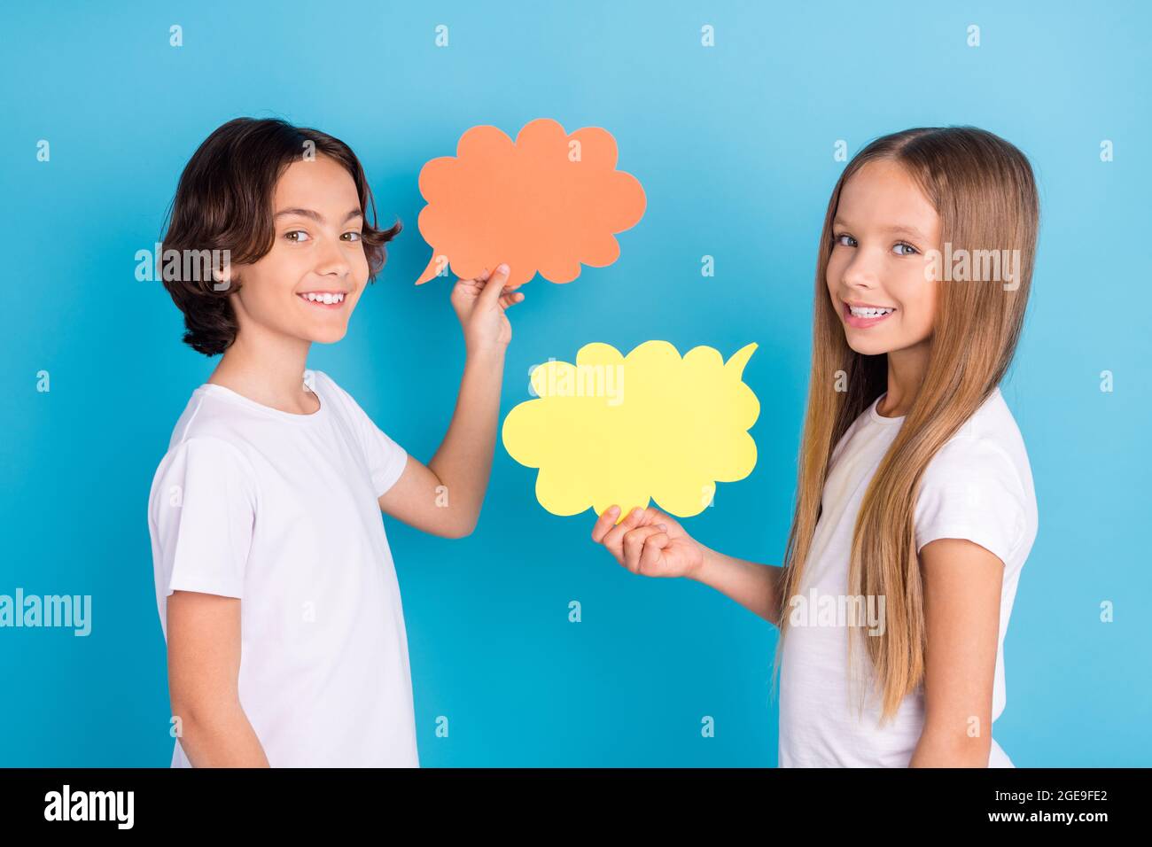 Foto von zwei geselligen Kinder kommunizieren Gegenwart Geist Wolke tragen weißen T-Shirt isoliert blauen Hintergrund Stockfoto