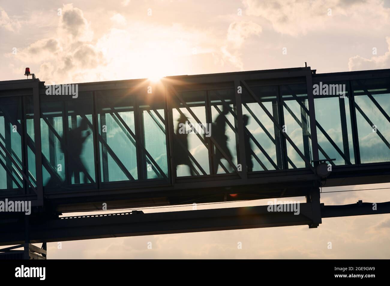 Silhouetten von Menschen, die am geschäftigen Flughafen laufen. Passagiere, die in die Bordbrücke gehen. Stockfoto