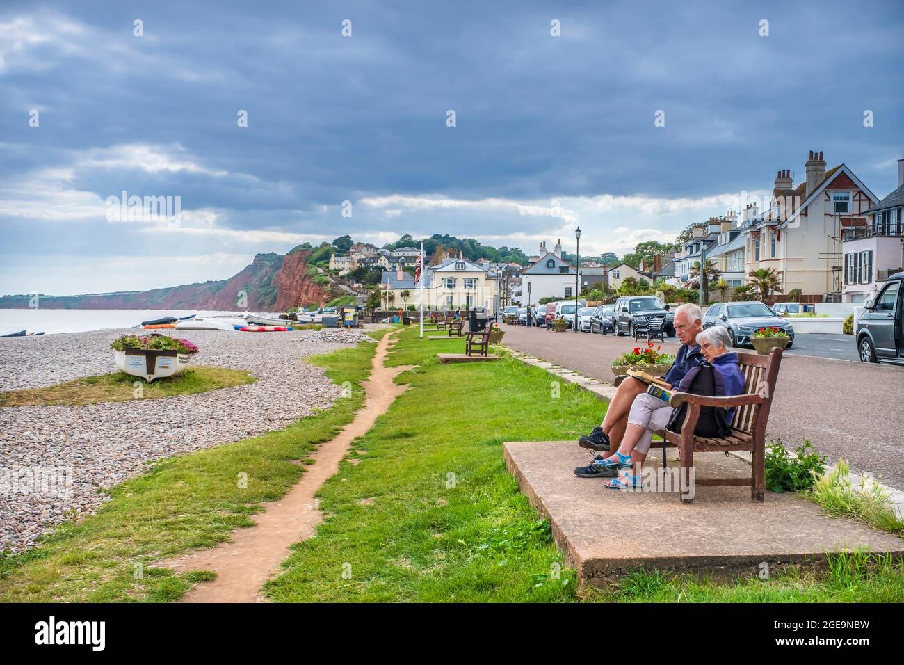 Zwei Rentner lesen auf einer Bank am Meer. Stockfoto