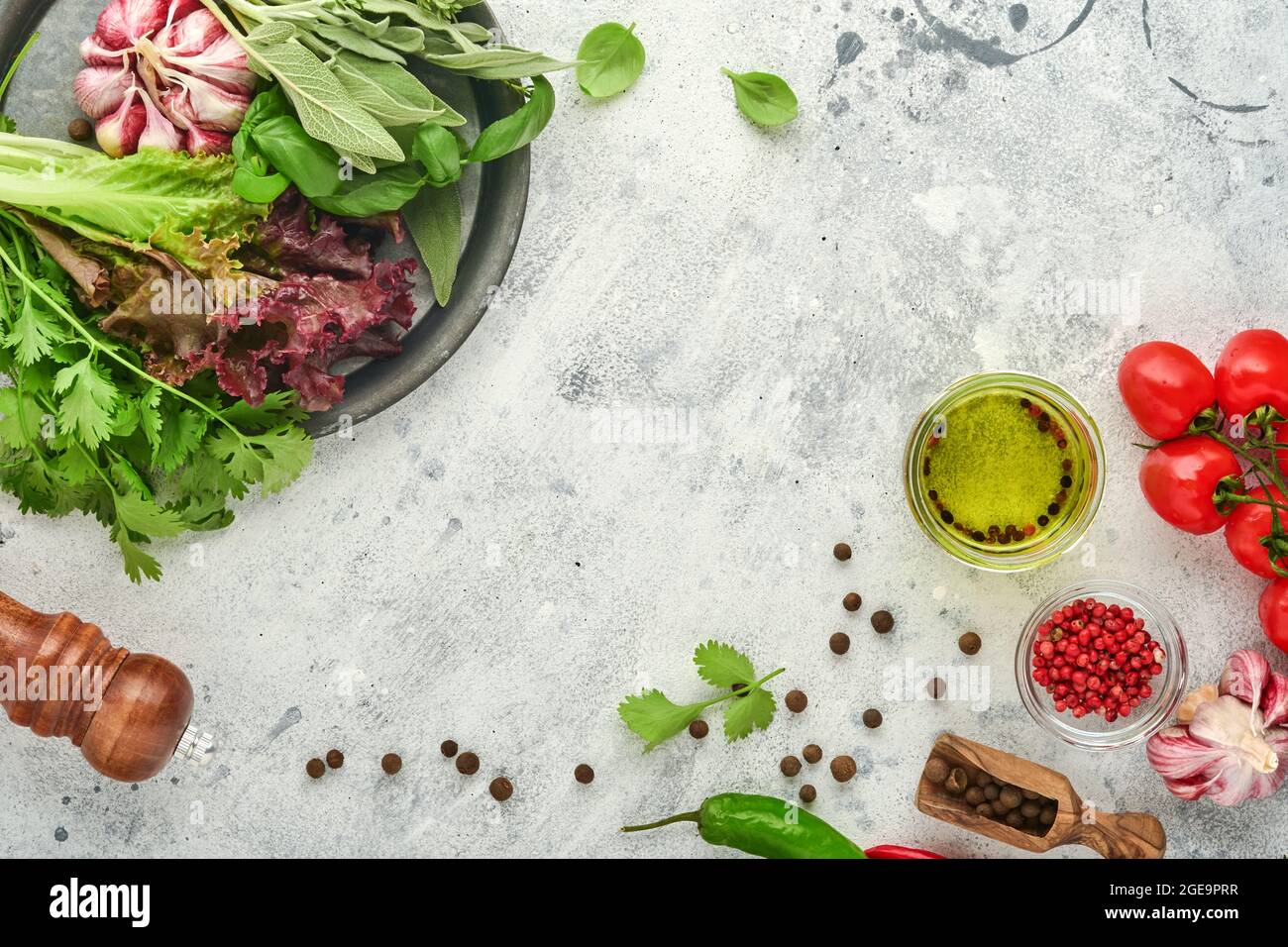 Hintergrund zum Kochen von Speisen. Frischer Safran, Knoblauch, Koriander, Basilikum, Kirschtomaten, Paprika und Olivenöl, Gewürze Kräuter und Gemüse bei hellgrauem sla Stockfoto