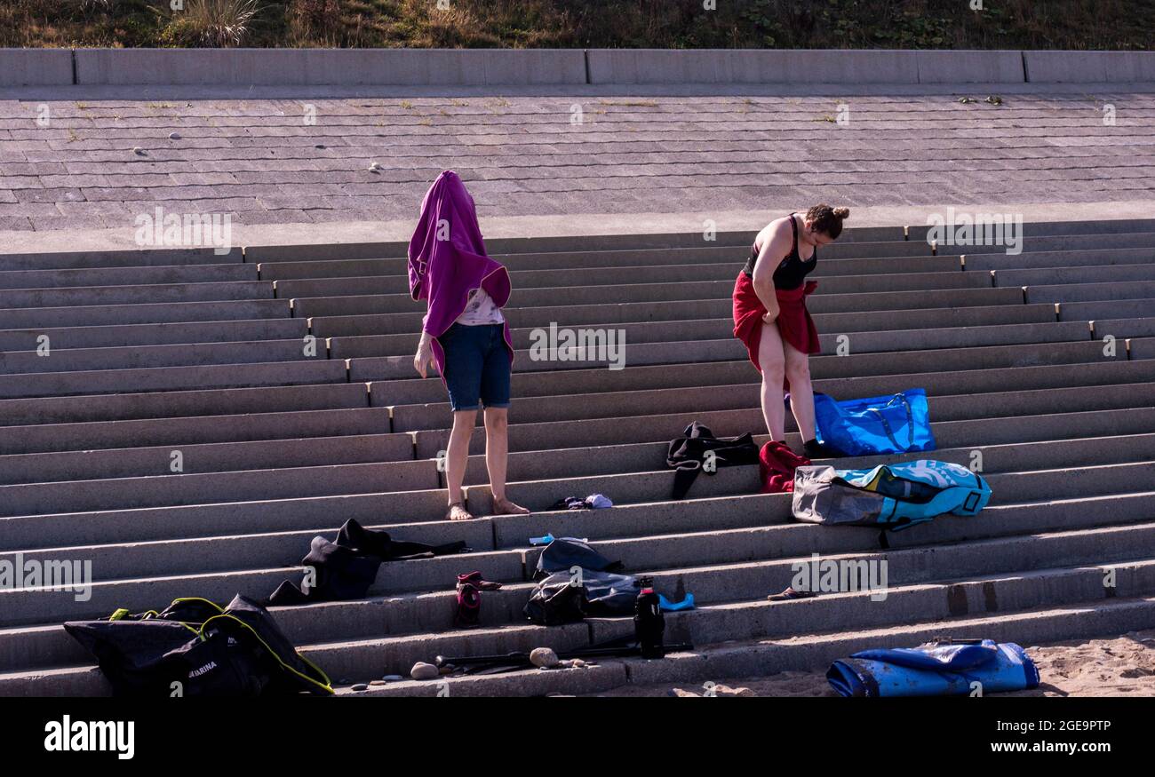 Touristen kleiden sich auf den Stufen am Strand in Whitby in England. Stockfoto