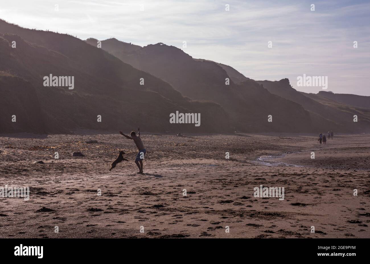 Mann spielt mit Hund am Strand in Whitby in England. Stockfoto