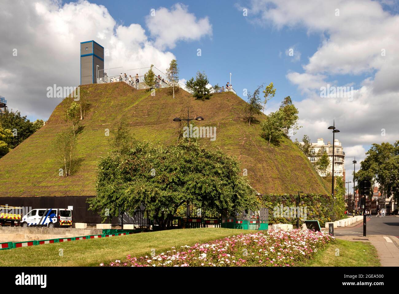 DER LONDONER MARMORBOGEN LIEGT AUF DEM HÜGEL MIT MENSCHEN AUF DER AUSSICHTSPLATTFORM UND EINEM SOMMERBLUMENBETT Stockfoto