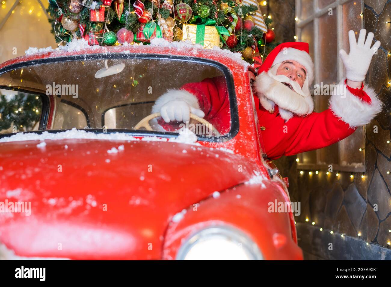 weihnachtsmann grüßt während der Fahrt mit einem roten Retro-Auto. Frohe  Weihnachten Stockfotografie - Alamy