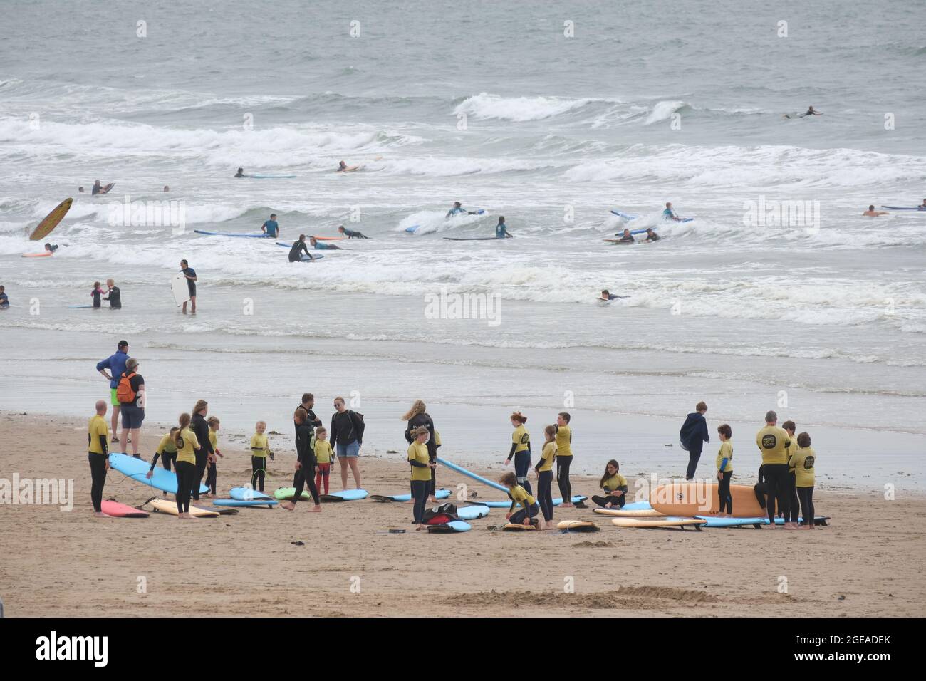 Gower, Swansea, Großbritannien. August 2021. Strandbesucher genießen am Strand Llangennith auf der Halbinsel Gower das Beste aus den für die Saison unbeständig kühlen Temperaturen und den windigen Bedingungen. Die Teilnehmer einer Surfschule treffen sich für ihren Unterricht. Kredit: Gareth Llewelyn/Alamy Stockfoto