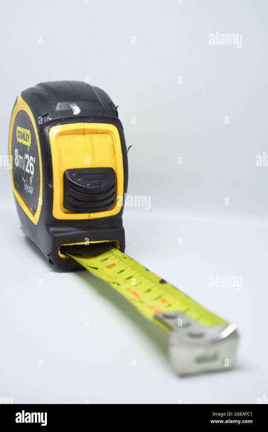 Ein schwarz-gelbes Maßband vor weißem Hintergrund Stockfoto