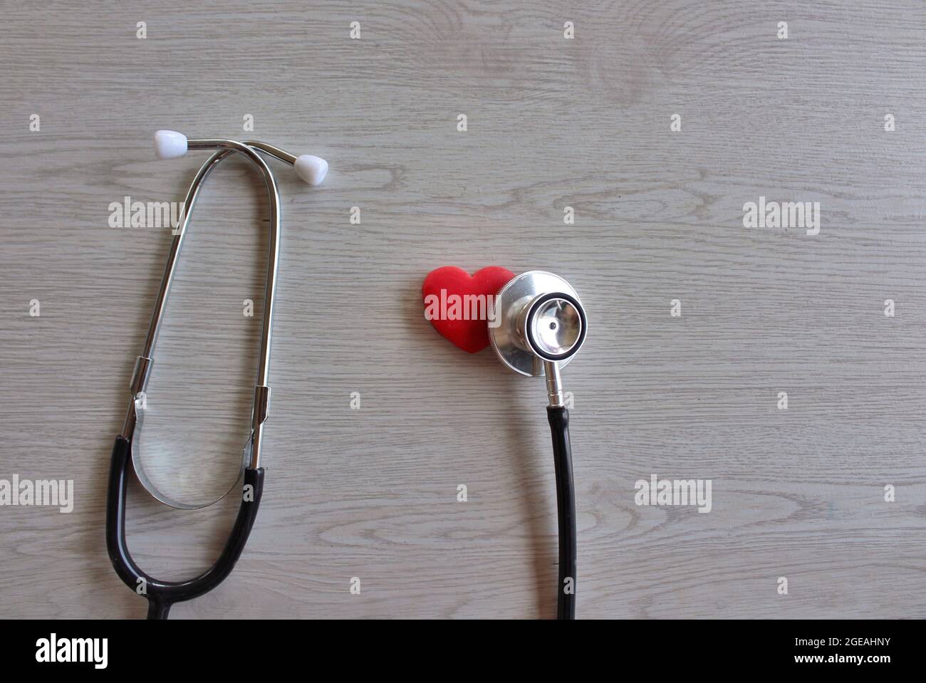 Rotes Herz und Stethoskop auf weißem Holzhintergrund. Gesundheitswesen und medizinisches Konzept Stockfoto