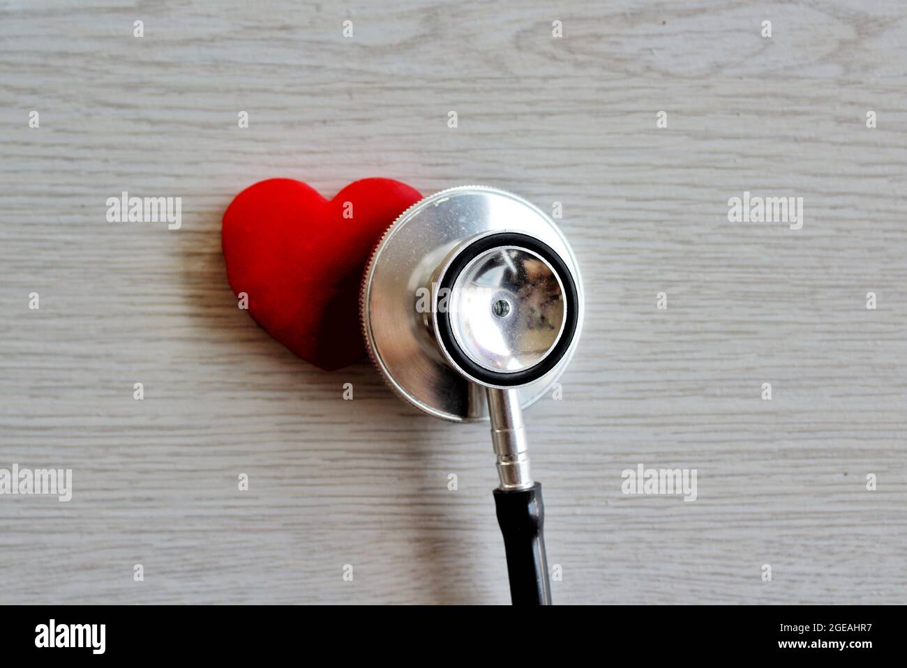 Rotes Herz und Stethoskop auf weißem Holzhintergrund. Gesundheitswesen und medizinisches Konzept Stockfoto