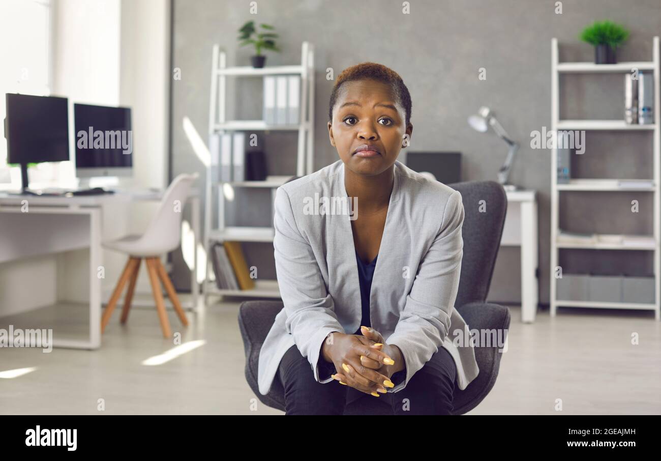 Unbeeindruckt enttäuschte Geschäftsfrau, die auf einem Bürostuhl saß und die Kamera ansah Stockfoto