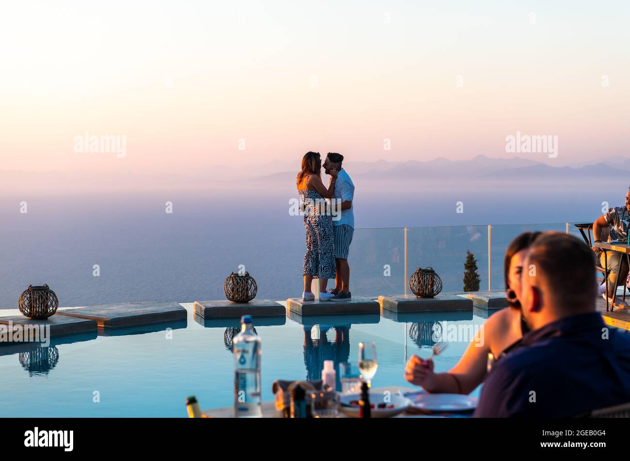 Insel Lefkada. Griechenland - 08.07.2021: Ein junges Paar, das Romantik und feines Essen am Pool mit fantastischem Meerblick genießt. Stockfoto