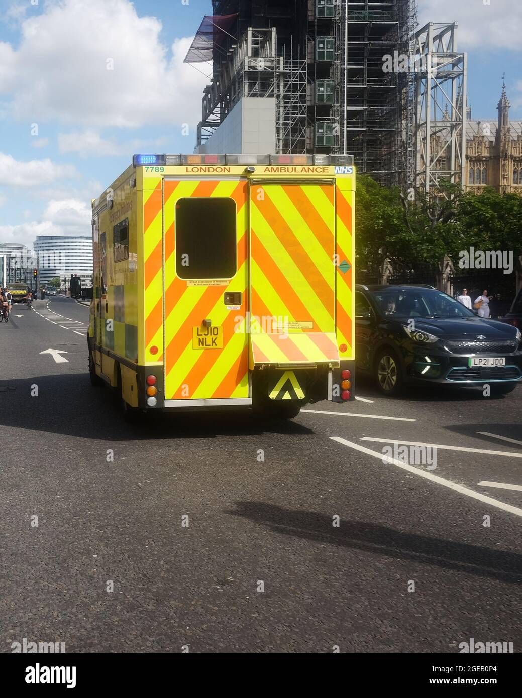 2021. August - Gelber Krankenwagen in London bei einem Anruf aus blauem Licht auf dem Parliament Square. Stockfoto