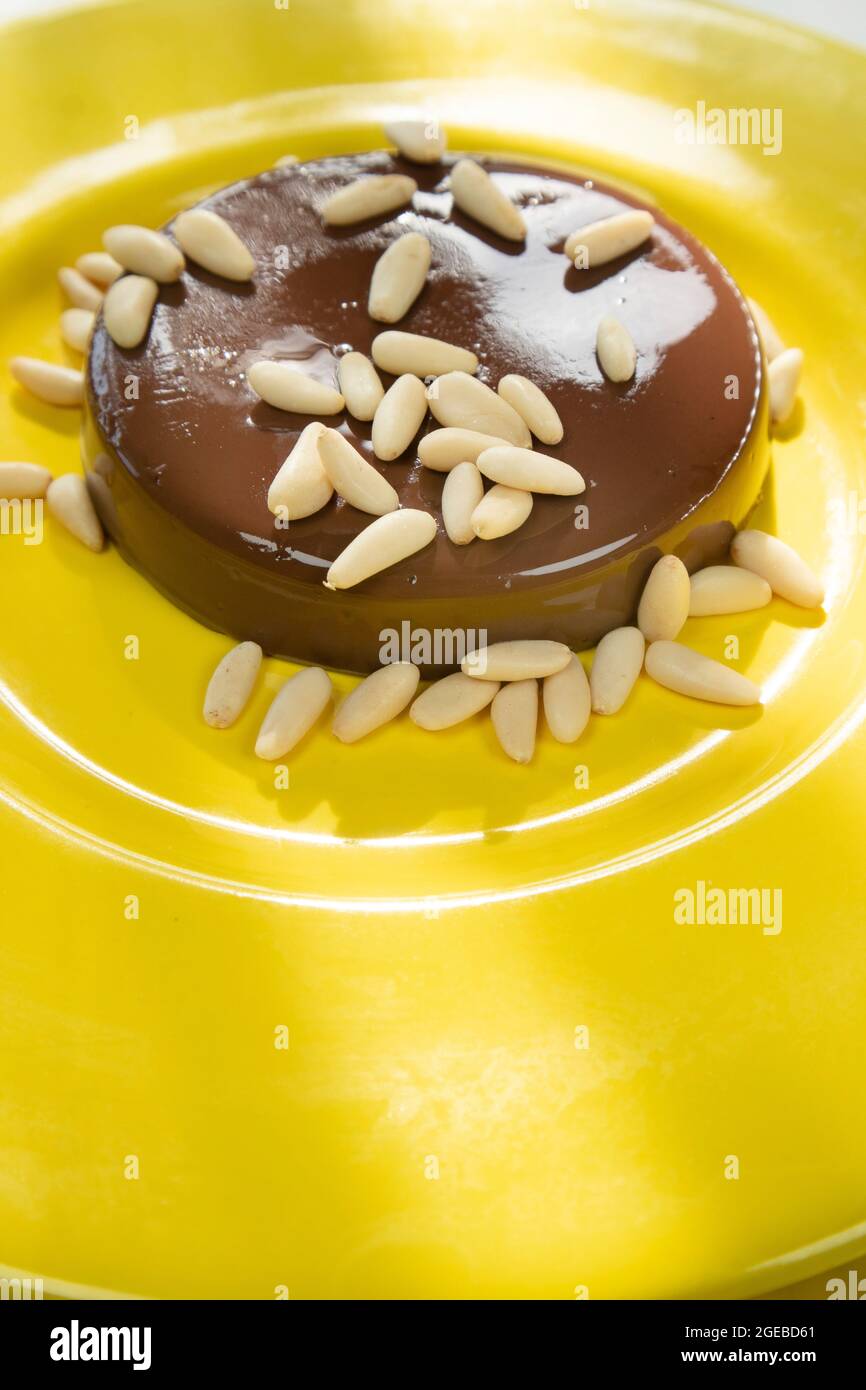 Fotografische Präsentation eines veganen Dessertes, Pudding mit Sojamilch, Kakao und braunem Zucker und Pinienkernen Stockfoto