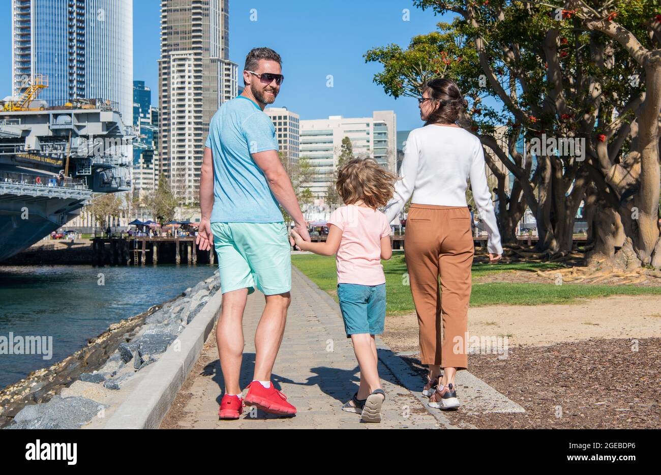 Rückansicht der jungen Familie, die mit Kind im Park spazierengeht, Familientag Stockfoto