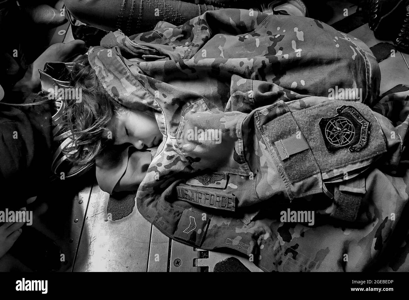 Ein afghanisches Kind schläft während eines Evakuierungsfluges aus Kabul, Afghanistan, am 18. August 2021 auf dem Frachtboden eines US Air Force C-17 Globemaster III, warm gehalten durch die Uniform von Airman First Class Nicolas Baron, C-17 Lastmaster. Das Air Mobility Command, das eine Flotte von Air National Guard, Air Force Reserve und Active Duty C-17 betreibt, hat zur Unterstützung des Verteidigungsministeriums Truppen ins Theater gebracht, um die sichere Ausreise und Umsiedlung von US-Bürgern, Empfängern von Sondereinreisevisa und gefährdeten afghanischen Bevölkerungen aus Afghanistan zu erleichtern. (Foto: 1. LT. Mark Lawson) Stockfoto