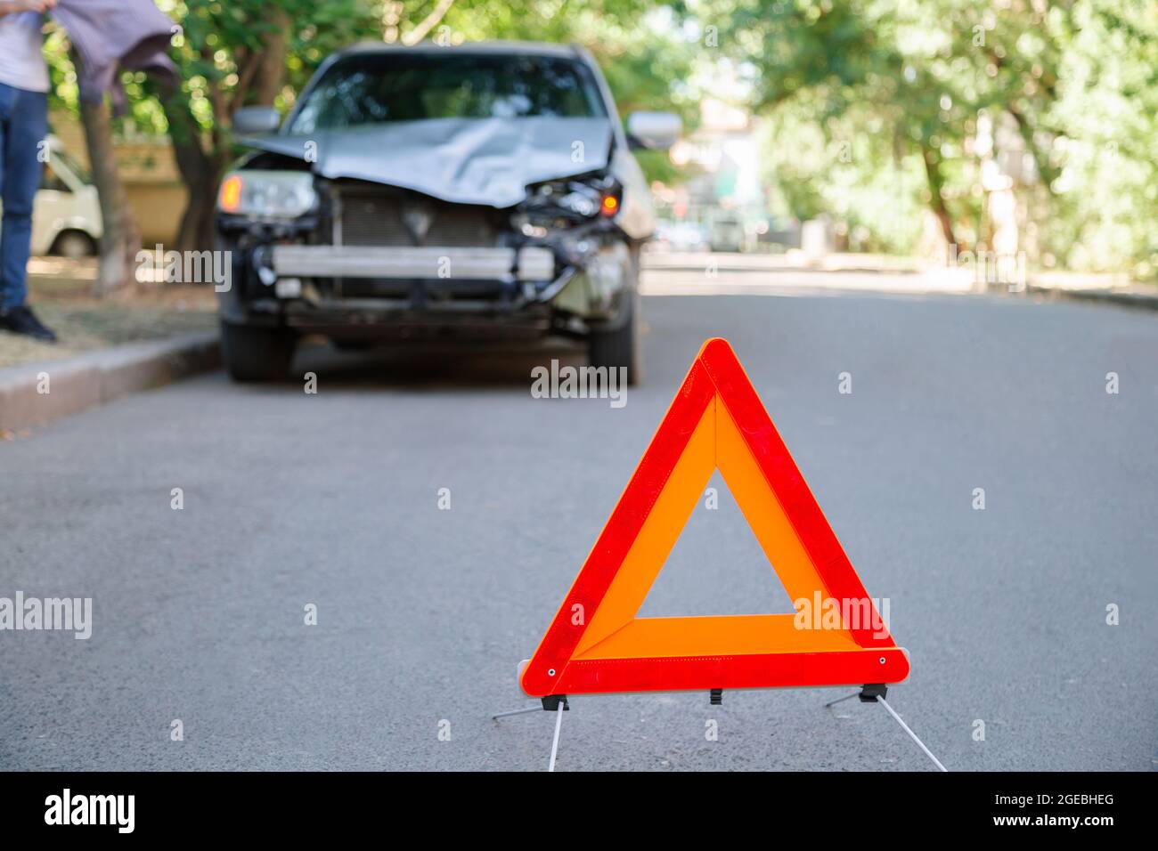 Rotes Dreieck Warnzeichen eines Autounfalls auf der Straße. Triangle vor dem zerstörten Auto im Sommer. Stockfoto