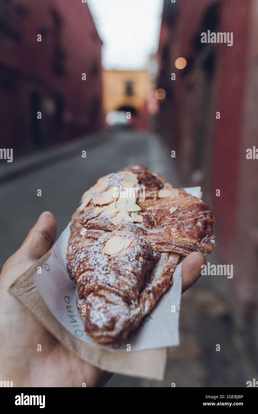 POV mit einem Mandelcroissant in der Hand Stockfoto