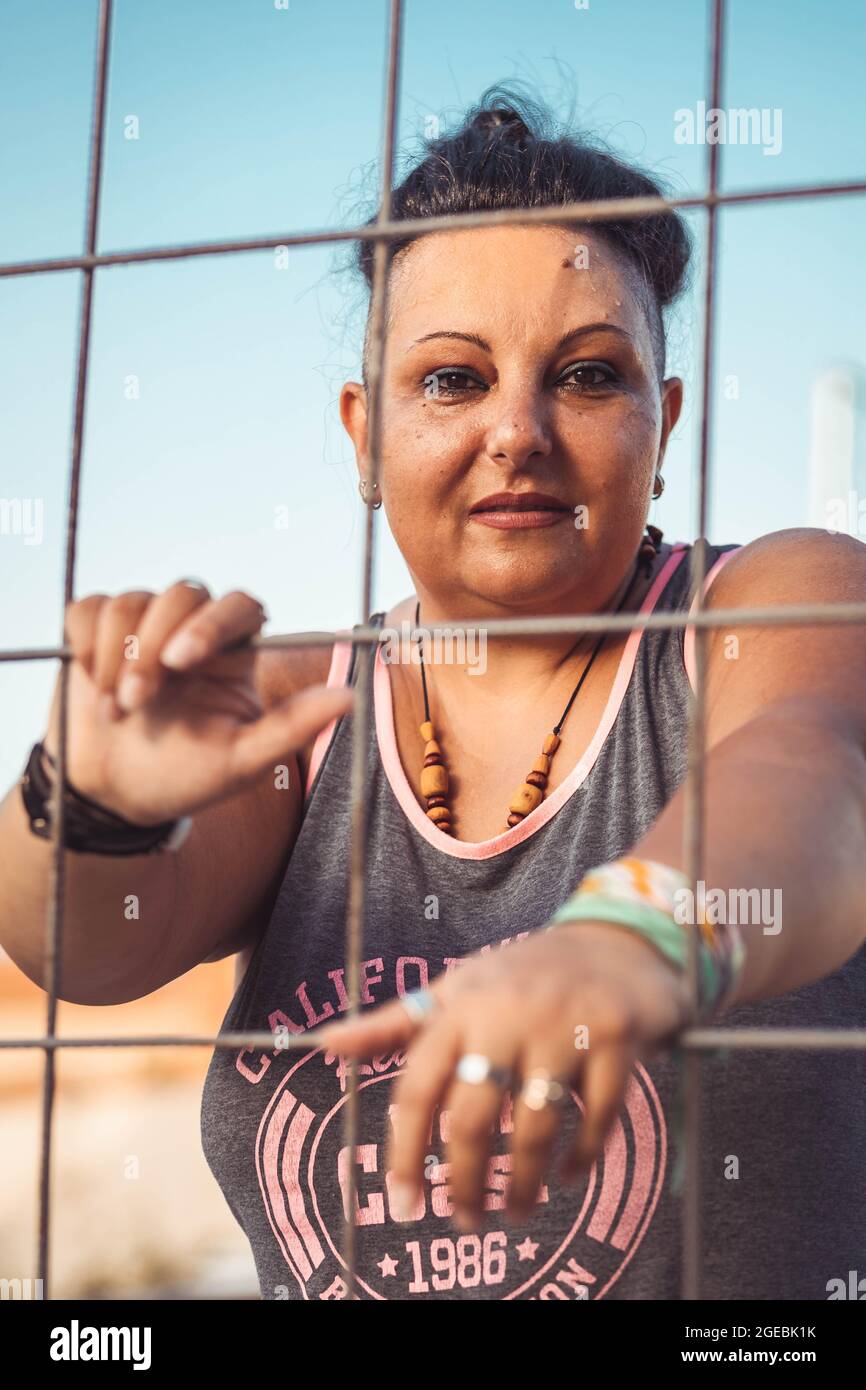 Positive Frau mittleren Alters mit Cherokee Haarschnitt. Schauen Sie durch den Draht Stockfoto
