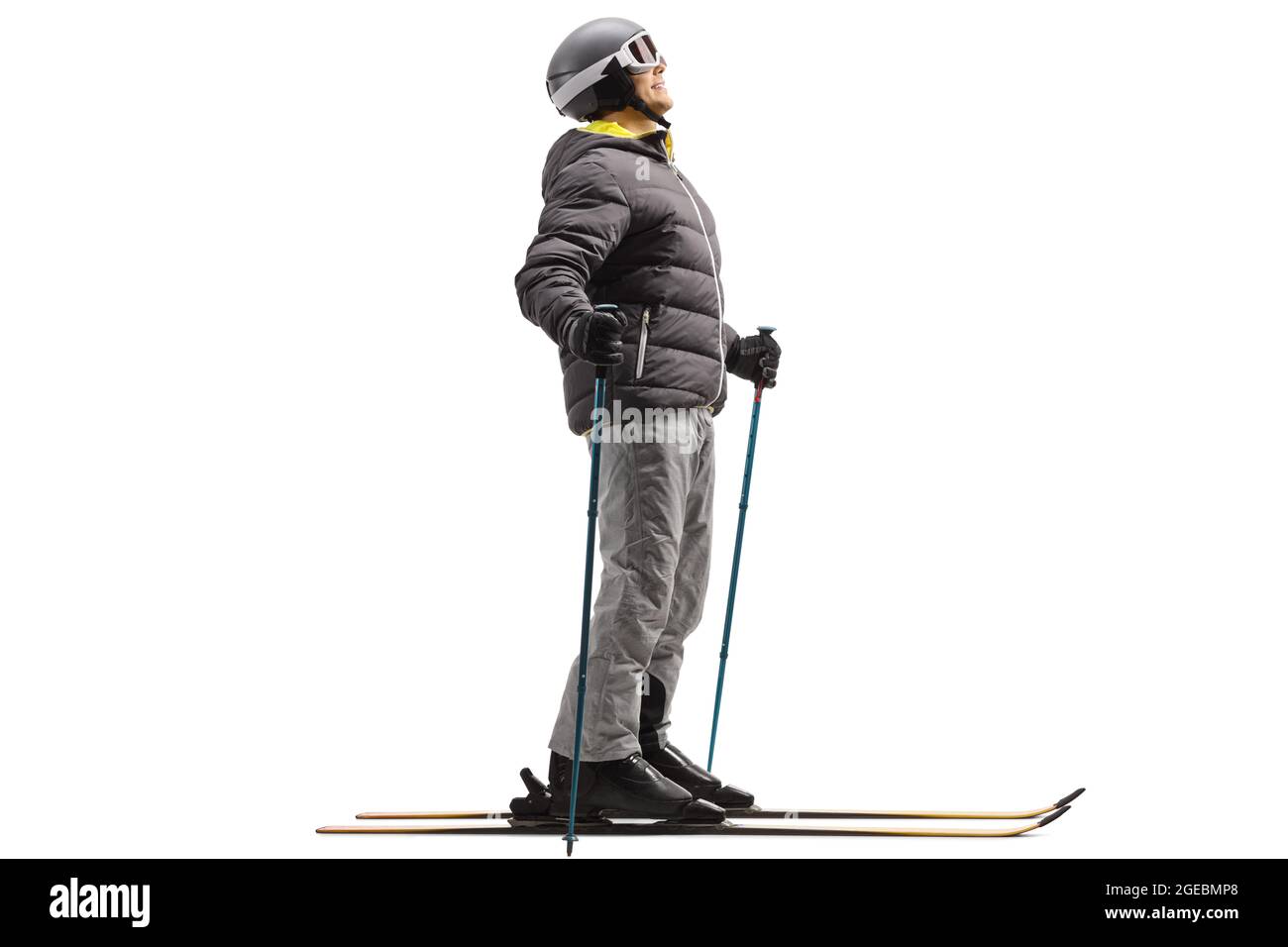 Ganzkörperaufnahme eines Mannes in Skijacke, Skischuhen und Helm mit einem Paar Ski, isoliert auf weißem Hintergrund Stockfoto