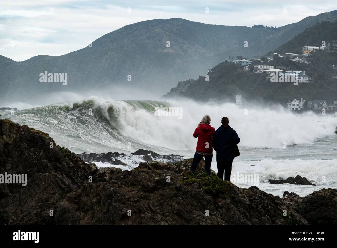 Frauen beobachten, wie riesige Wellen in Houghton Bay, Wellington, Neuseeland, brechen Stockfoto