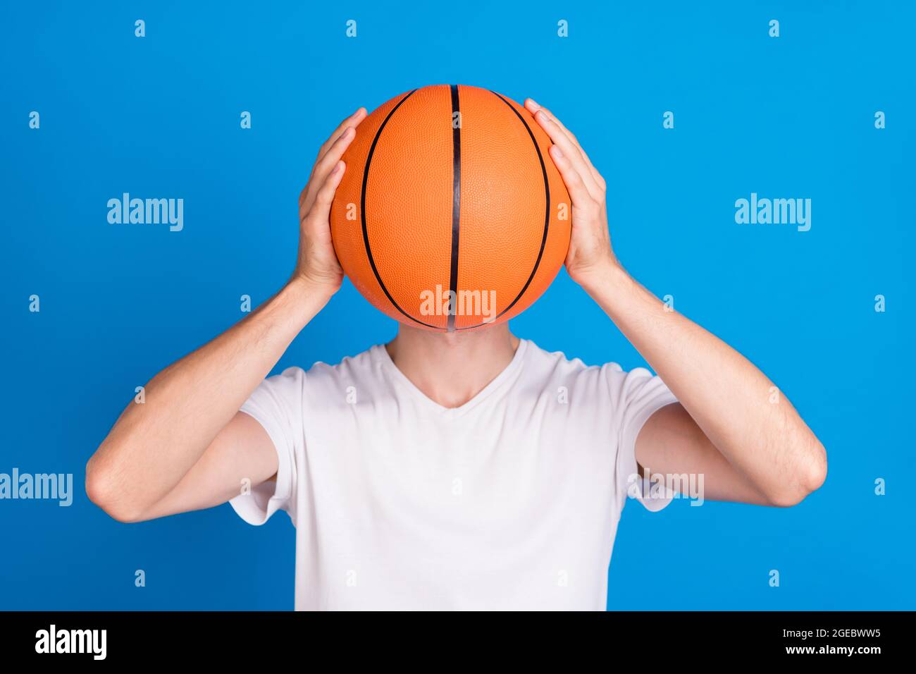 Foto von jungen Mann halten Hände Basketball-Spiel spielen Abdeckung nahes Gesicht isoliert auf pastellblauen Hintergrund Stockfoto