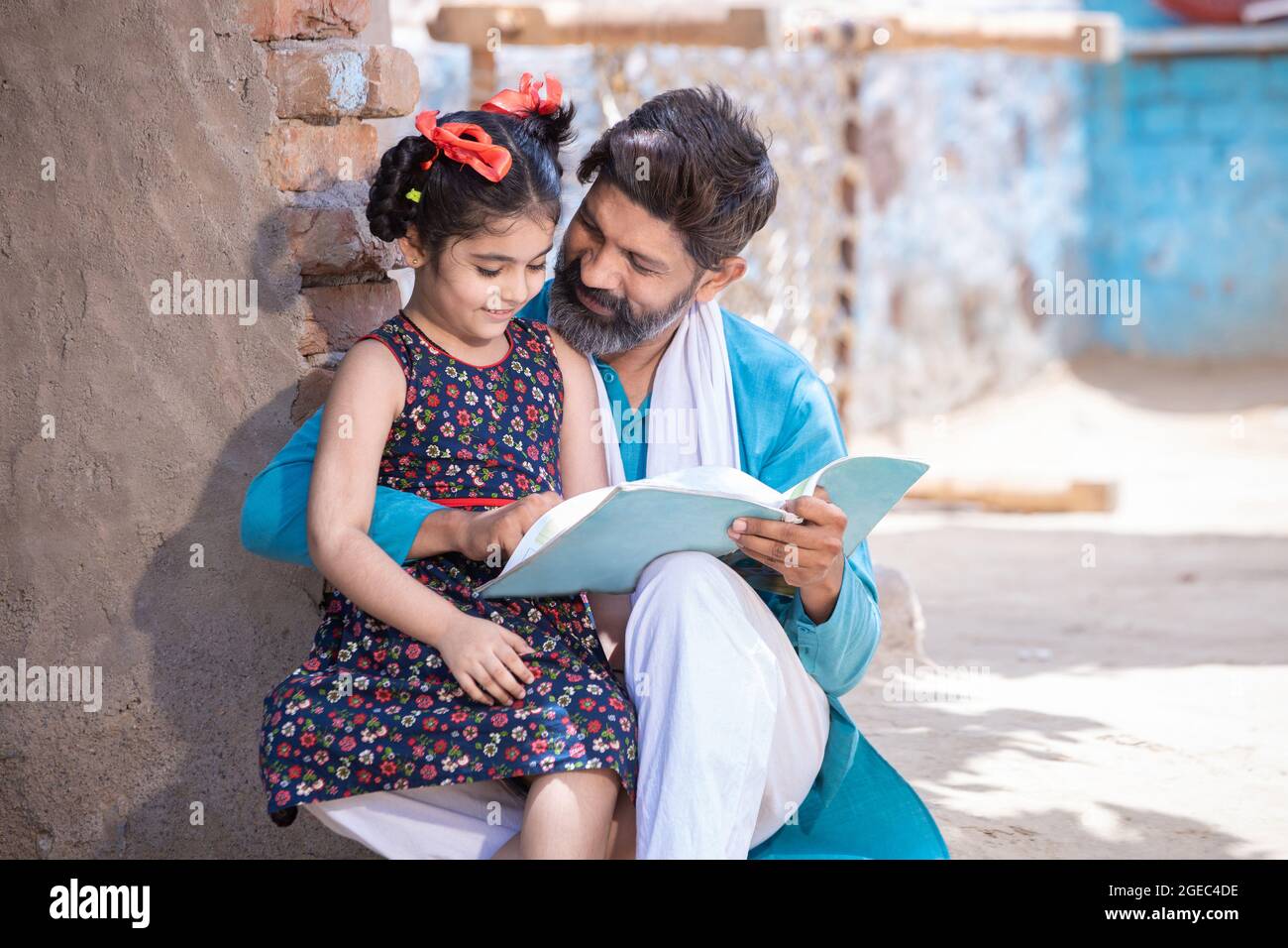 Glücklich ländlichen indischen Vater hilft seiner Tochter in Studien, entzückende kleine Dorf Mädchen Kind hält Notebook studieren außerhalb des Hauses. Mann lehrt und Stockfoto