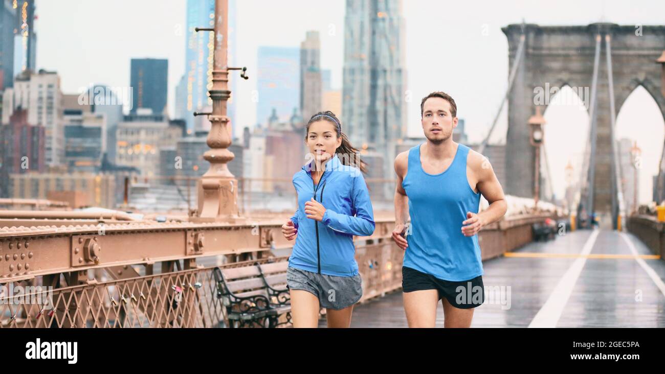 Laufen Paar Läufer joggen draußen in der Stadt Straße unter regen Banner. Asiatische Frau und kaukasischen Mann Läufer und Fitness-Sport-Modelle Training für Stockfoto