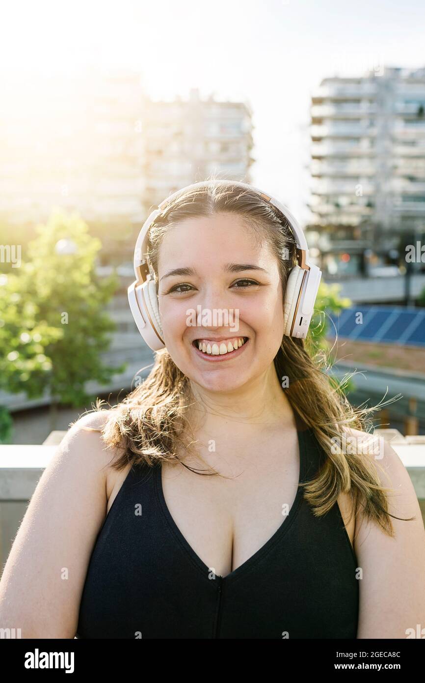 Porträt einer glücklichen, sportlichen, kurvigen Frau mit Kopfhörern nach dem Training Stockfoto