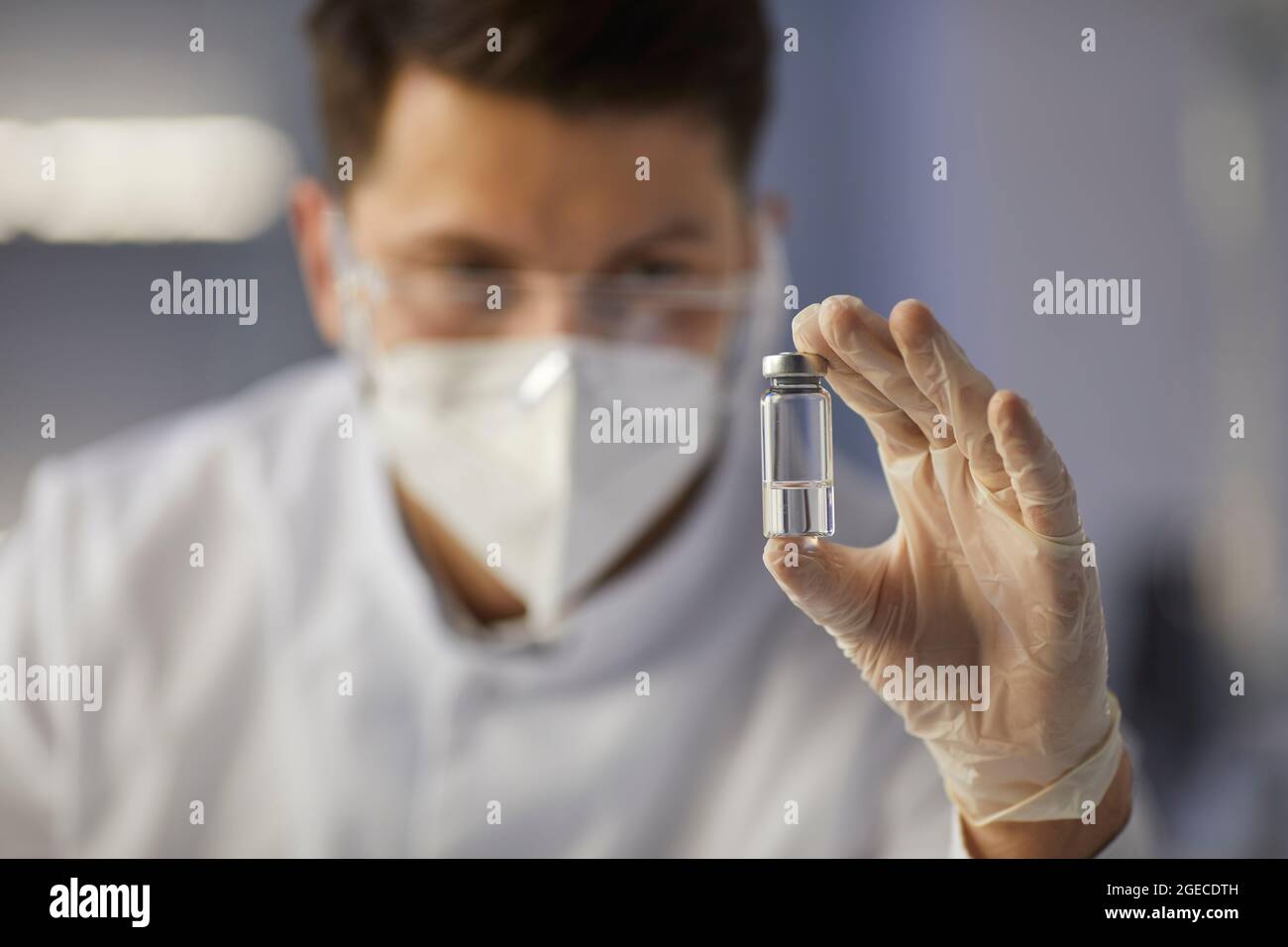 Glasampulle mit einer klaren Flüssigkeit in den Händen eines männlichen Arztes oder Laborassistenten. Stockfoto