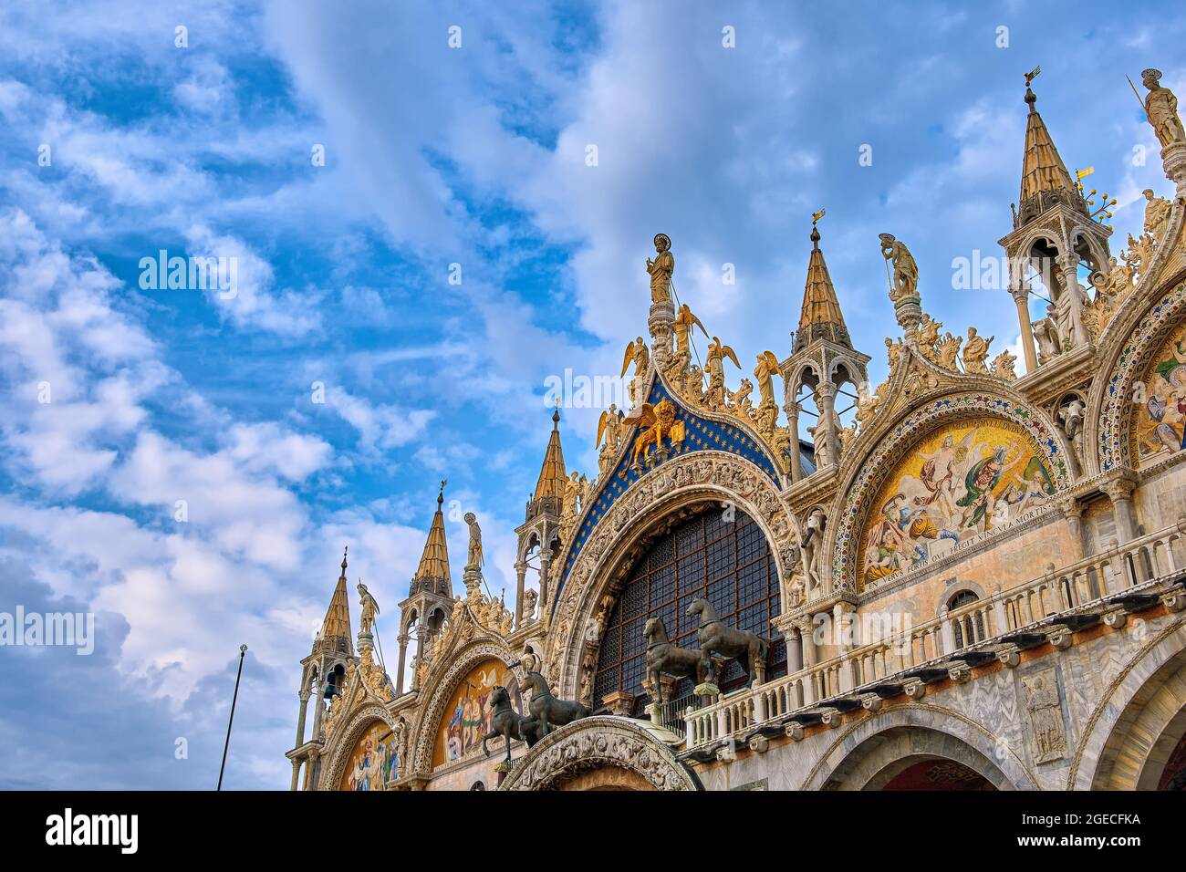 Nahaufnahme der Hauptfassade der Markukathedrale in Venedig. Italien. UNESCO-Weltkulturerbe, blauer Himmel, Wolken, Mosaiken, Marmorschnitzereien, Statuen Stockfoto