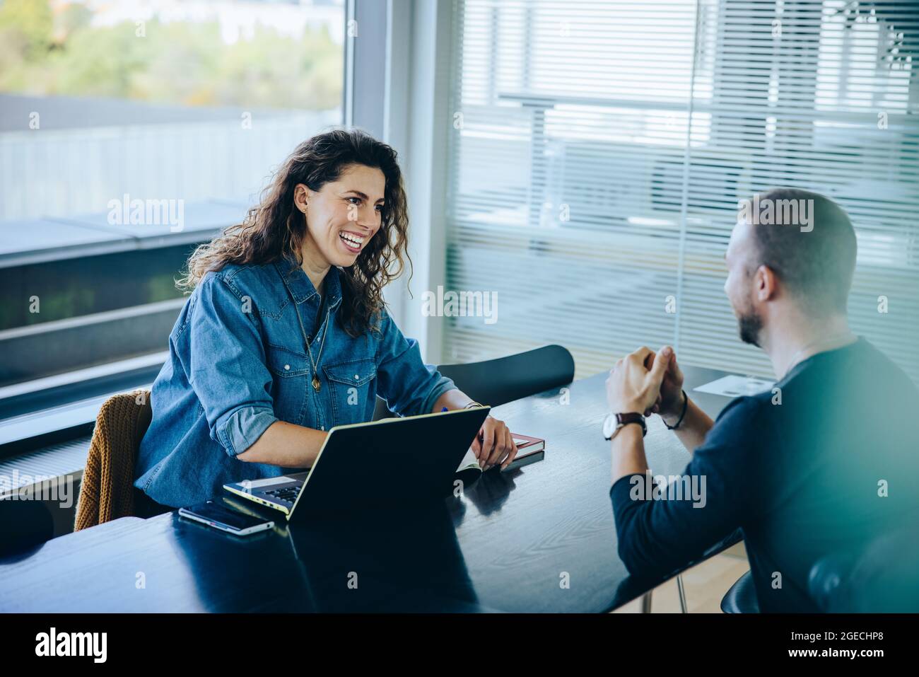 Lächelnde Geschäftsfrau, die ein Bewerbungsgespräch führt. Freundliche Personalbeschaffung Manager interviewte jungen Mann in Büro-Vorstandszimmer. Stockfoto