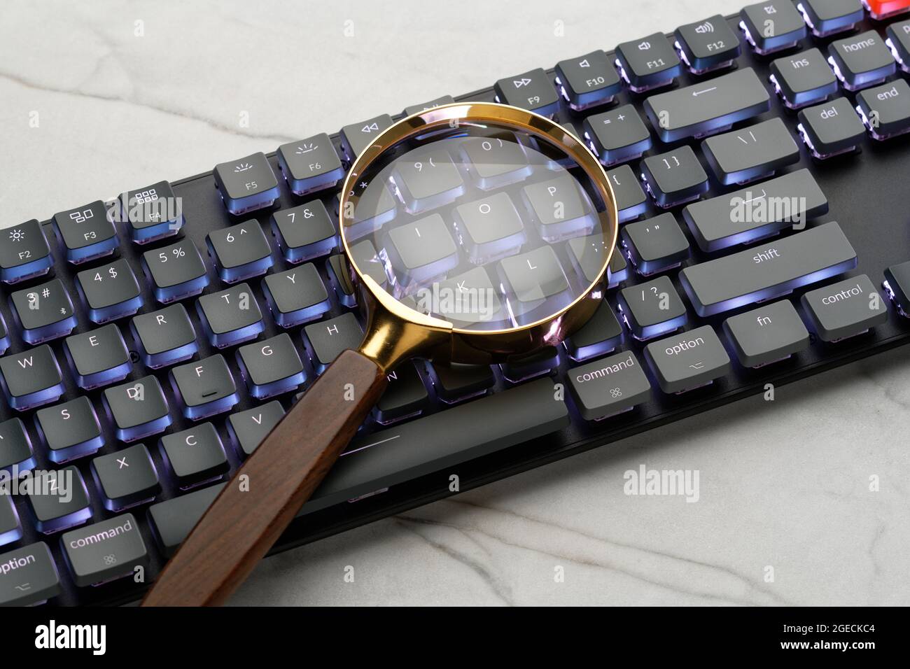 Lupe auf einer Computertastatur. Illustriert eine Suche im Internet. Suchen von Dingen mithilfe eines Computers. Stockfoto