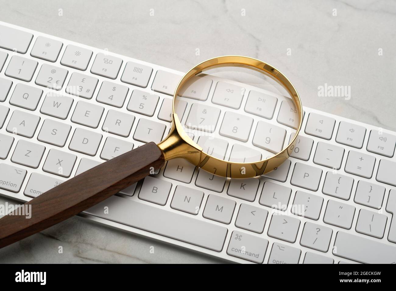 Lupe auf einer Computertastatur. Illustriert eine Suche im Internet. Suchen von Dingen mithilfe eines Computers. Stockfoto