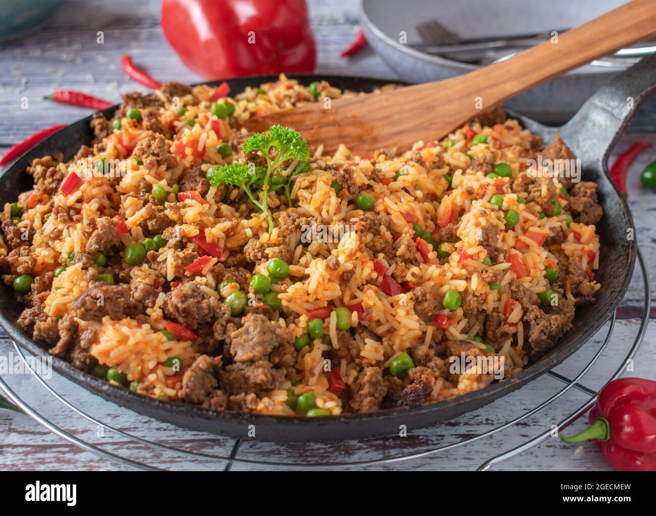 Serbische Hackfleischpfanne mit Djuvec-Reis aus Paprika, grünen Erbsen und Ajvar heiß auf einem Küchentisch serviert Stockfoto