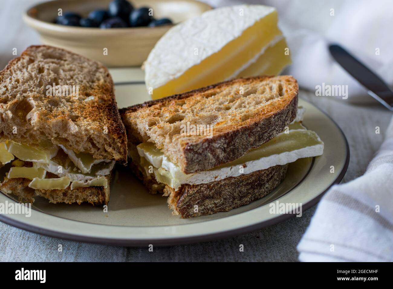 Sandwich aus geröstetem Sauerteig und deutschem Sauermilchkäse auf einem rustikalen Teller Stockfoto