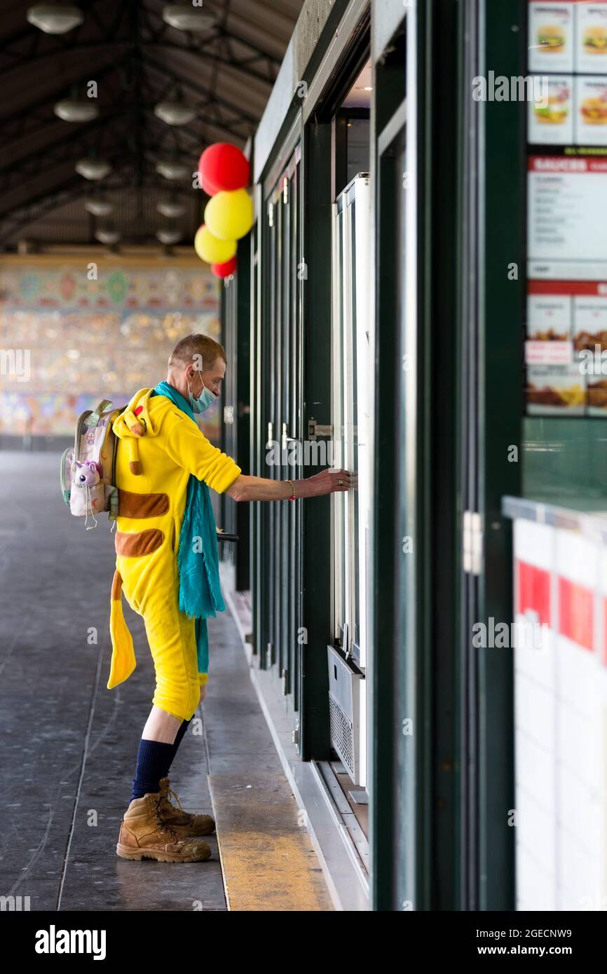 Melbourne, Australien, 3. August 2020. Ein Mann, der einen Tiger-Anzug-Einteiler und eine Gesichtsmask trägt, wird gesehen, wie er während der COVID-19 in Melbourne, Australien, einen Kaffee an der Flinders Street Station kauft. Während Melbourne seinen ersten Tag der Beschränkungen der Stufe 4 erlebt, sowie eine Ausgangssperre von 20:00 bis 5:00 Uhr, kündigte Premier Daniel Andrews heute den Plan für die Stilllegung für alle außer den wichtigsten Unternehmen für mindestens die nächsten 6 Wochen an. Victoria verzeichnete weitere 429 COVID-19-Fälle und 13 weitere Todesfälle, was die Gesamtzahl der aktiven Fälle in den Bundesstaaten auf 6,489 brachte. Kredit: Dave Hewison/Speed Media/Alamy Live Nachrichten Stockfoto