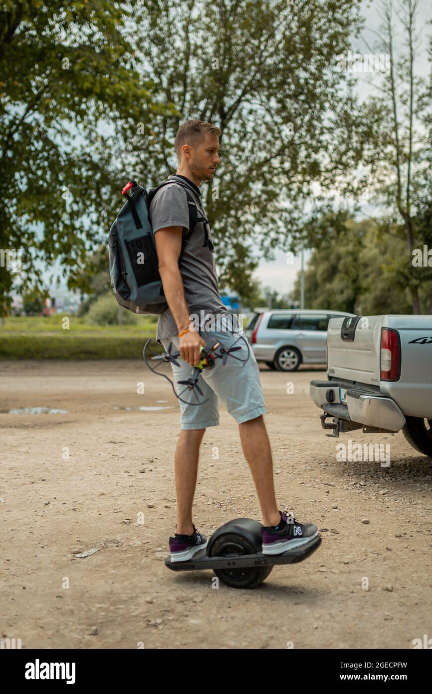 Mann mit Rucksack auf einem motorisierten Skateboard mit einem Rad auf dem Bürgersteig Stockfoto