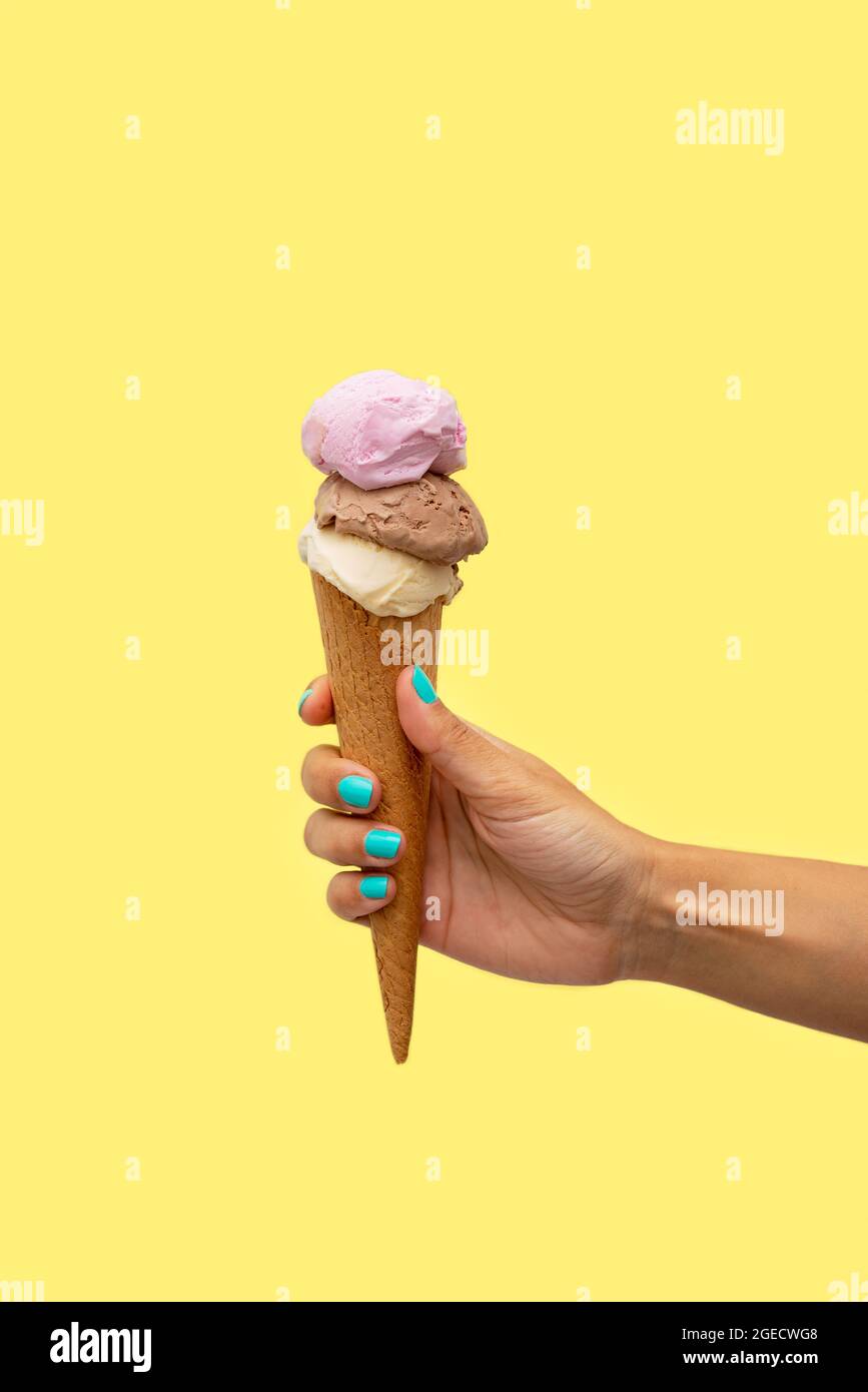 Die Hand der Frau hält ein Eis auf gelbem Hintergrund Stockfoto