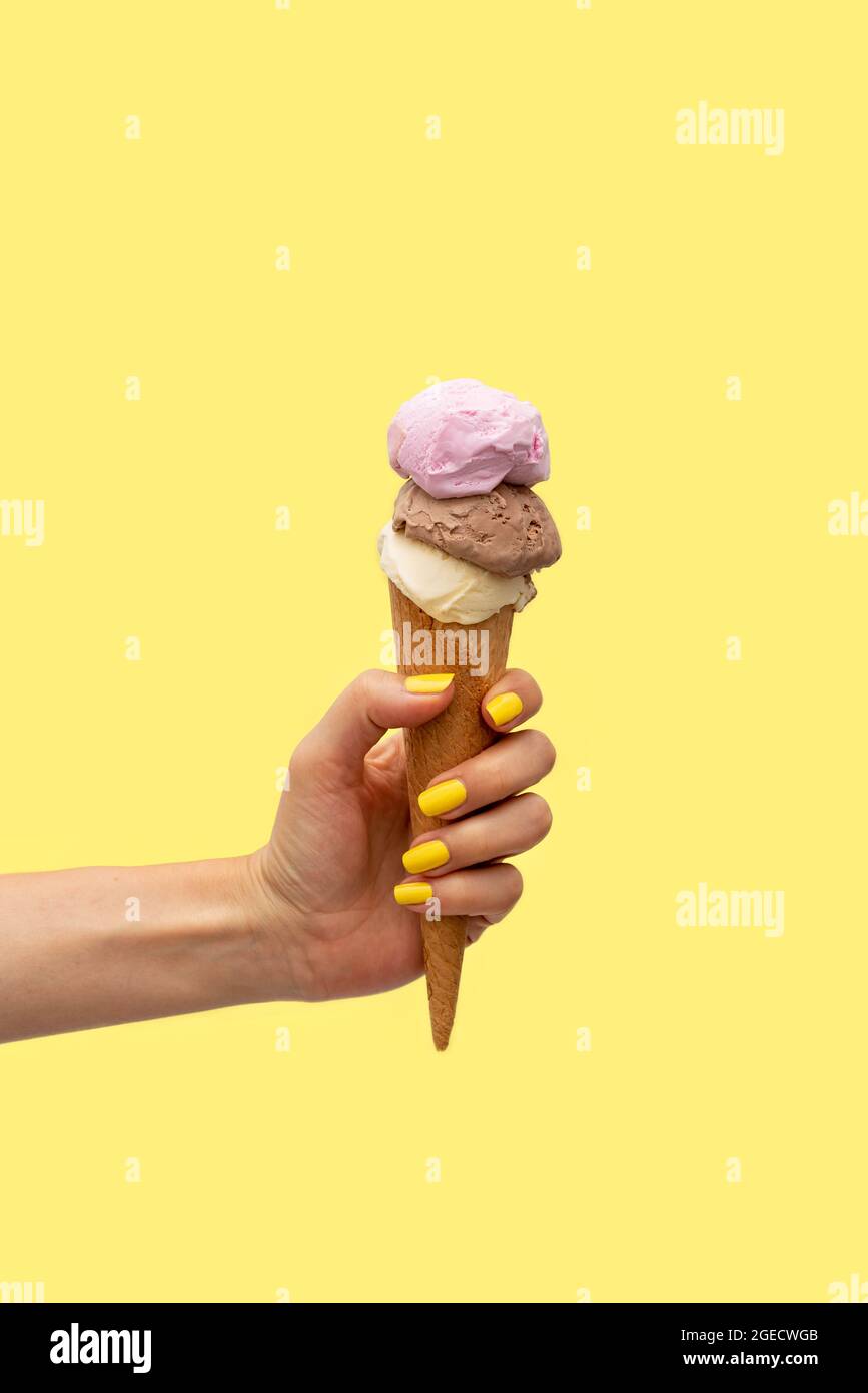 Die Hand der Frau hält ein Eis auf gelbem Hintergrund Stockfoto