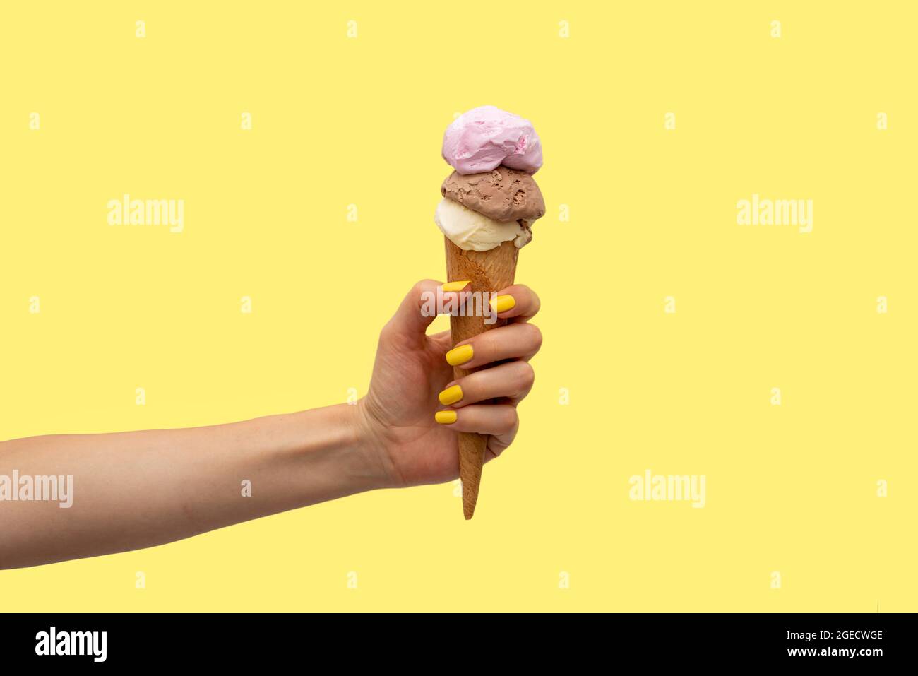 Die Hand der Frau hält ein Eis auf gelbem Hintergrund Stockfoto
