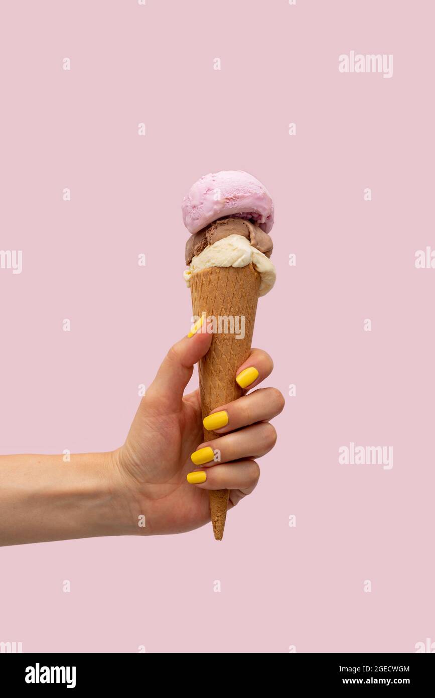 Die Hand der Frau hält ein Eis auf einem rosa Hintergrund Stockfoto