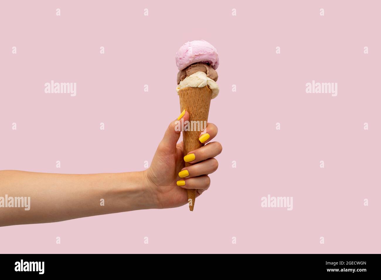 Die Hand der Frau hält ein Eis auf einem rosa Hintergrund Stockfoto