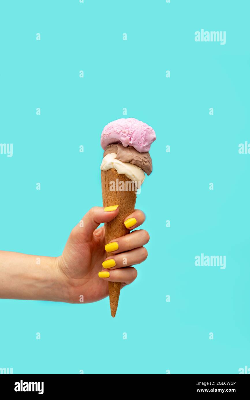 Die Hand der Frau hält ein Eis auf einem hellblauen Hintergrund Stockfoto