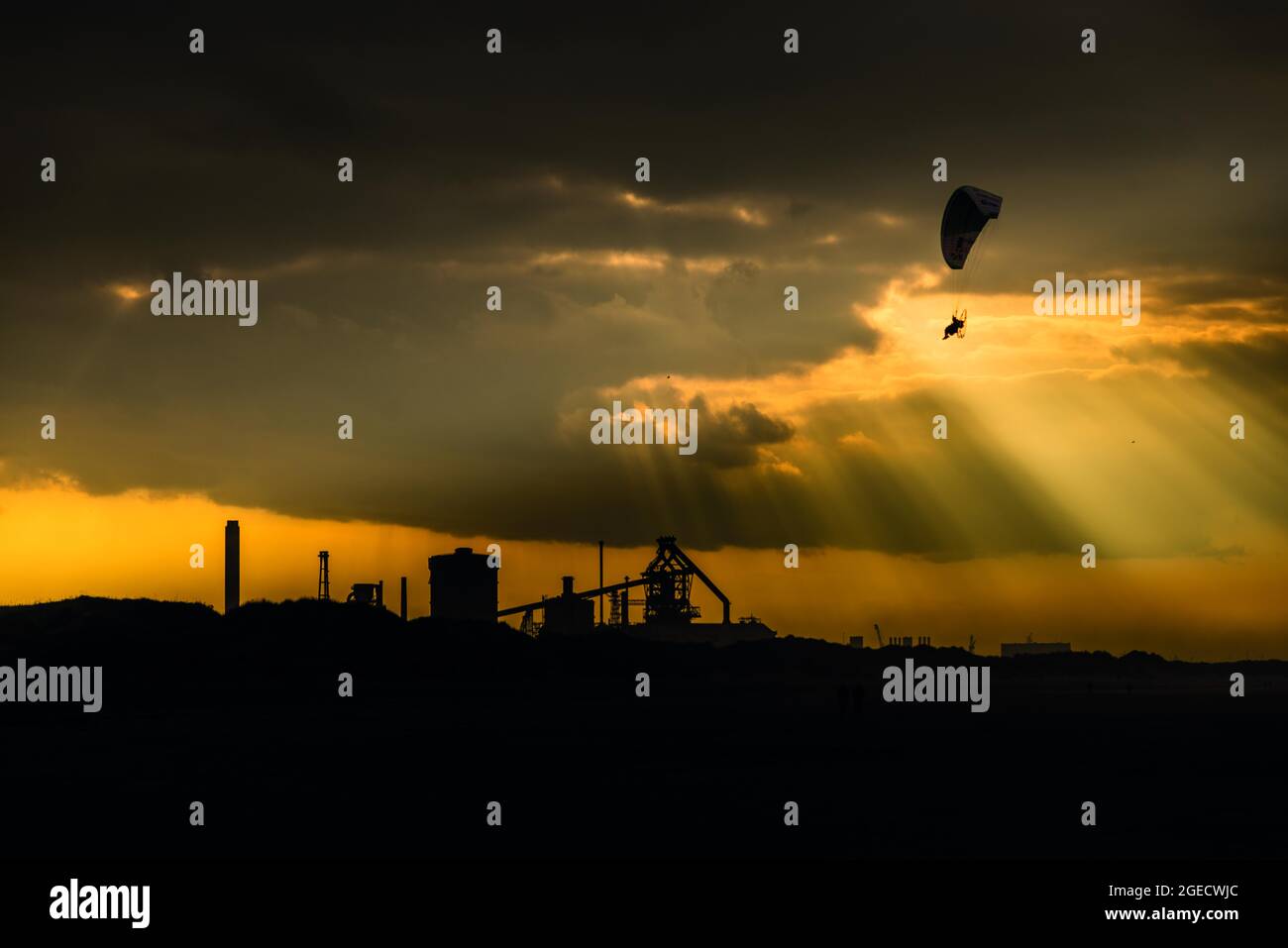 Paragliding über Coatham Beach, Redcar mit dem ehemaligen Stahlwerk in der Ferne. Stockfoto