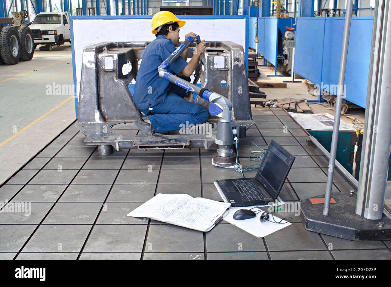 Ein Techniker verwendet in einer Metallfabrik ein Messgerät und einen Laptop. Stockfoto